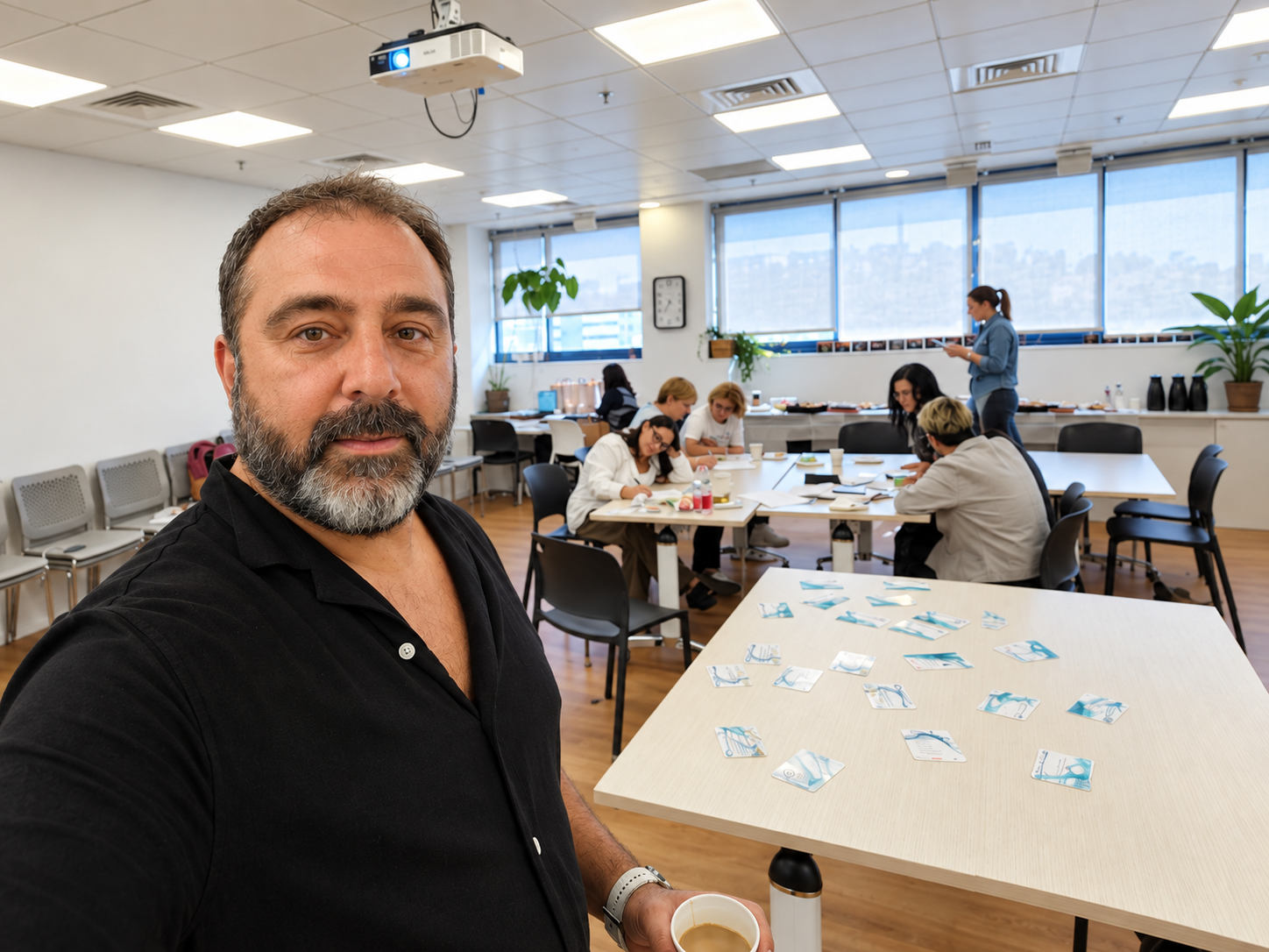 יום צוות עם קלפי Fusion 5 פרושים על השולחן ומשתתפים עובדים סביב שולחנות
